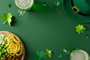Yonca şapkası, köpüklü bira ve bir tabak abur cuburla Aziz Patrick Günü kutlamaları için canlı yeşil bir ortam. İrlanda bayramı, selamlama ve yeşil temalı etkinlikler için şenlik havası ideal