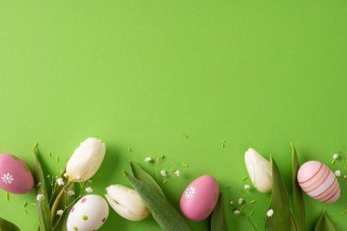 Canlı Paskalya sahnesi, pastel yumurtalar ve yeşil bir zeminde beyaz laleler. Şenlikli renkler, çiçekler ve semboller bahar tatilleri için kutlama, sevinç ve mevsimsel kutlamaları iletir