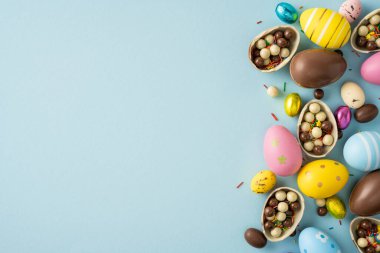 Pastel boyalı yumurtalar ve yumuşak mavi arka planda hazırlanmış çikolatalı şekerlemelerin yer aldığı Paskalya kutlamanız kutlu olsun.