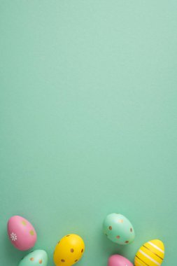 Mutlu Paskalya dikey kutlamaları ve renkli pastel yumurtalar mevsimlik kartlar ve bahar tasarımları için cömert bir telif alanına sahip yeşil arka planda düzenlenmiştir.