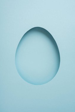 Kartlar, şablonlar ve bahar kutlama tasarımları ve modelleri için ideal pastel mavi arka planda kağıt yumurta kesiminin yer aldığı dikey Paskalya kutlamanız kutlu olsun.