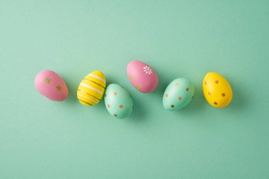 Yumuşak yeşil arka planda boyanmış pastel yumurtalarla mutlu Paskalya kutlamaları. Bahar kutlamaları ve şenlikli dekorlar.
