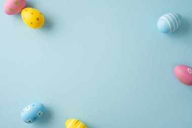 Soluk mavi bir zemin üzerine dizilmiş yumuşak pastel yumurtalar. Mutlu Paskalya kutlamaları ve bahar kutlamaları.