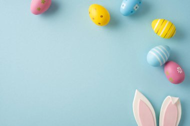 Pastel dekore edilmiş yumurta, tavşanlı kulak desteği ve açık mavi arka plan ile bayram kartı, bahar promosyonu, el işi projesi ve şenlikli mevsimlik konsept sunan Paskalya kutlamanız kutlu olsun.