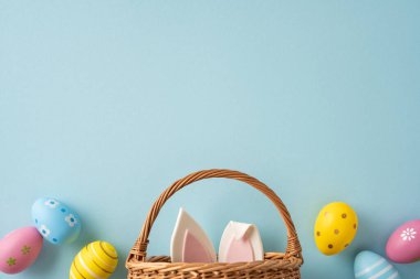 Yumuşak pastel arka planda örülmüş yumurta ve tavşan kulaklı bir sepetin olduğu Paskalya kutlamanız kutlu olsun. Mevsimlik tebrik kartları ve bahar tatili promosyonları için mükemmel.
