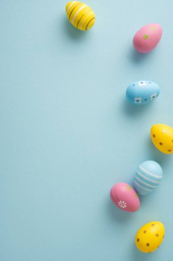 Açık mavi arka planda süslü pastel yumurtaların yer aldığı Paskalya bayramınız kutlu olsun.