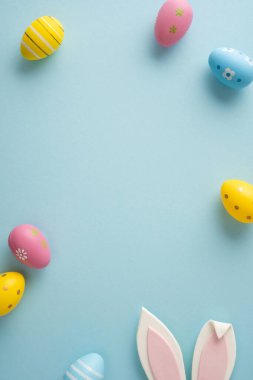 Pastel boyanmış yumurta ve tavşan kulaklarıyla Paskalya kutlamaları mutlu sonbahar tanıtımları ve şenlikli dekorasyon için ideal yumuşak mavi arka plan.