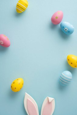 Mutlu Paskalya kutlamaları Pastel boyalı yumurtalar, dekoratif tavşan kulakları ve yumuşak bahar tonları mevsimlik kartlar ve tasarımlar için minimum düzlük olarak düzenlenmiştir.