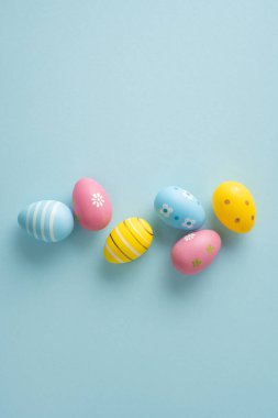 Mutlu Paskalya dikey kutlamaları ve süslü pastel yumurtalar bahar tatili ve mevsimsel dekorasyon için yumuşak mavi bir arka planda düzenlenmiştir.