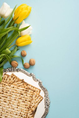 Süslü gümüş bir tabakta matza, sarı ve beyaz lale, ceviz ve yumuşak bahar tonları mevsimsel bir bayram için dikey olarak düzenlenmiştir.