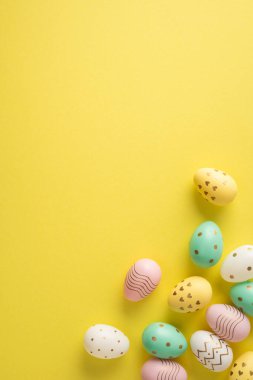 Parlak Mutlu Paskalya dikey kompozisyonu. Sarı arka planda pastel süslemeli bir yumurta. Bahar kutlamasını ve mevsimlik dekorasyonu çağrıştırıyor.