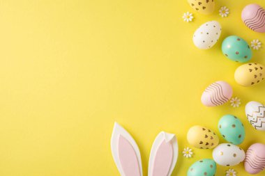 Pastel yumurta, tavşan kulağı ve papatya süslemelerinin yer aldığı mutlu Paskalya sahneleri mevsimsel selamlama ve tatil tasarımı için parlak sarı bir arka planda düzenlenmiştir.