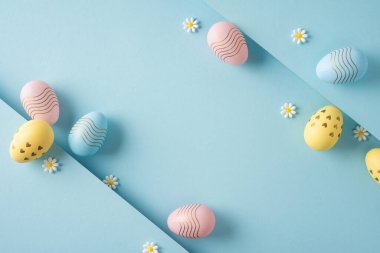 Pastel süslemeli yumurtalar ve yumuşak mavi kağıt katmanlarına yerleştirilmiş papatya çiçekleri mevsimlik kartlar ve şenlik dekorları için ideal bir bahar kompozisyonu oluşturan mutlu Paskalya kutlamaları.