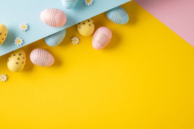 Mutlu Paskalya pastel yumurtaları ve papatya süslemeleri rengarenk tasarım ve şenlikli mevsimsel modda minimum bahar kutlaması için parlak sarı bir arka planda düzenlenmiştir.