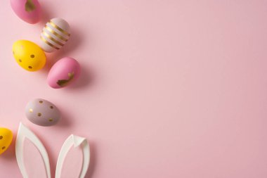 Pastel Easter egg line with bunny ears on pink background, festive spring celebration