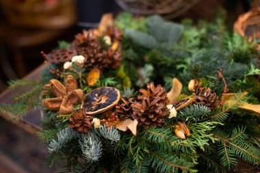 Tahta elementler ve konilerle süslenmiş Noel çelengi.