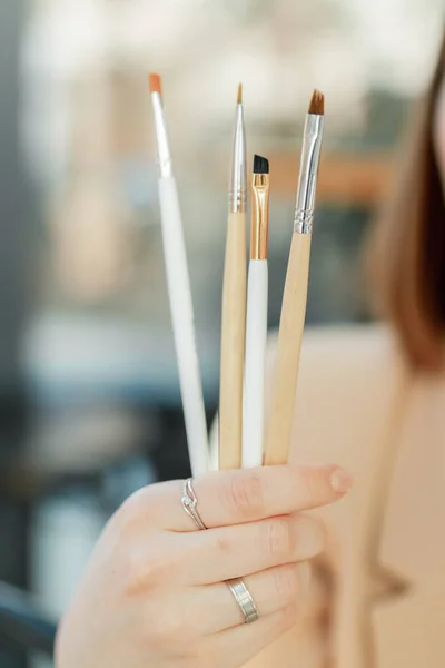 Eyebrow brushes in a hand of an artist