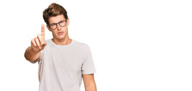 Yakışıklı, beyaz bir adam, günlük kıyafetler ve gözlük takıyor. Parmağını kaldırmış ve kızgın bir ifade takınıyor. 