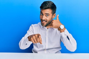 İş kıyafetleri giymiş yakışıklı İspanyol bir adam masaya oturmuş gülümsüyor telefonda konuşuyor ve seni işaret ediyor. Ara beni.. 