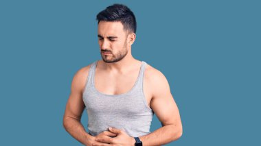 Mayo giyen genç ve kolsuz tişörtlü bir adam midesi üstünde çünkü hazımsızlık, acı verici bir hastalık ve kendini iyi hissetmiyor. Ağrı kavramı. 