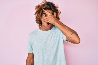 Gündelik kıyafetler giyen genç İspanyol adam şok içinde yüzünü ve gözlerini kapayarak utanmış ifadesiyle parmaklarından bakıyor.. 