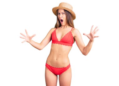 Güzel esmer bir kadın bikini giymiş, deli gibi bağırıyor, agresif bir ifadeyle bağırıyor ve kollarını kaldırıyor. hüsran kavramı. 