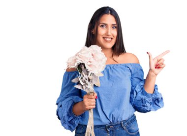 Genç, güzel esmer kadın elinde buketle gülümsüyor. 