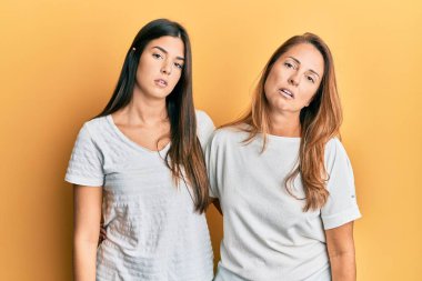 Latin kökenli anne ve kız çocukları günlük beyaz tişört giyiyorlar. Uykulu ve yorgun görünüyorlar. Yorgunluktan ve akşamdan kalmalıktan bitkinler.. 