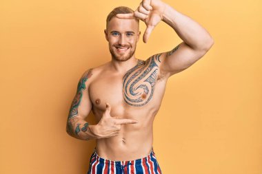 Mayo giyen, mayosuz, gülümseyen, elleri ve parmakları gülen yüzlü genç beyaz bir adam. yaratıcılık ve fotoğrafçılık kavramı. 