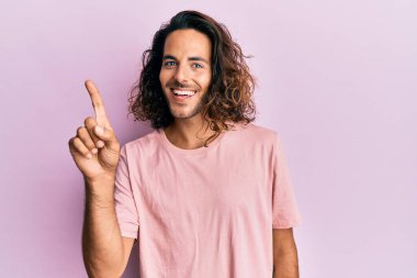 Uzun saçlı, sıradan kıyafetler giyen, bir fikri olan ya da soru soran mutlu bir yüzü olan genç yakışıklı bir adam. 