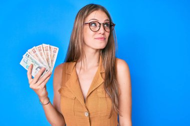 Genç sarışın kız krallığı elinde tutuyor gülümsüyor ve yan tarafa bakıyor ve düşünüyor.. 