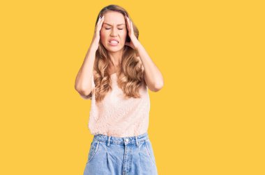 Sarışın, elleri kafasında, günlük kıyafetler giyen, stres yüzünden başı ağrıyan güzel beyaz bir kadın. migren ağrısı. 