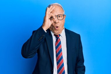 İş elbisesi ve kravat takan kıdemli beyaz adam şaşırmış yüz ifadesiyle şaşırmış ve parmaklarından içeri bakıyor. İnançsız ifade. 