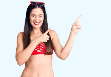 Bikini giyen, gülümseyen ve kameraya bakan beyaz, güzel bir kadın.. 