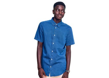 Genç Afro-Amerikan adam günlük kıyafetler giyiyor gülümsüyor yan tarafa bakıyor ve düşünüyor. 