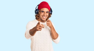 Genç İspanyol adam müzik dinliyor kulaklıkla kamerayı mutlu ve komik yüzüyle işaret ediyor. iyi enerji ve titreşimler. 