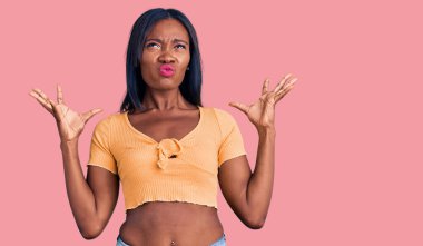 Genç Afro-Amerikalı kadın gündelik kıyafetler giyip deli gibi bağırıyor, agresif bir ifadeyle bağırıyor ve kollarını kaldırıyor. hüsran kavramı. 