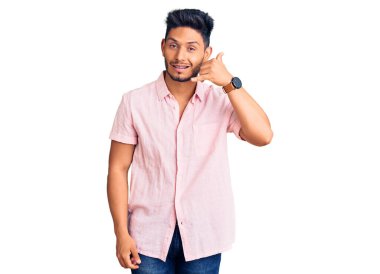 Yakışıklı Latin Amerikalı genç adam, sıradan bir yaz gömleği giyiyor, gülümsüyor, telefonla el ve parmak hareketleri yapıyor, telefonda konuşuyor gibi. iletişim kavramları. 