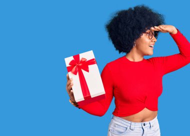 Genç Afro-Amerikalı kız elinde çok mutlu ve gülümseyen bir hediyeyle başlarını kaldırıp uzaklara bakıyor. arama kavramı. 