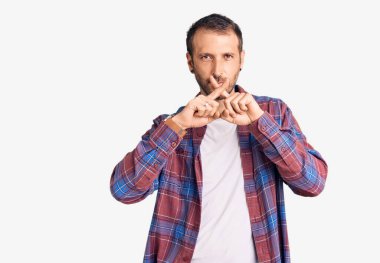 Genç ve yakışıklı bir adam günlük kıyafetler giyiyor. Reddedilme yüz ifadesi. Eksi işareti yapıyor. 