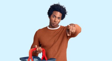 Yakışıklı Afro saçlı, süpermarket alışveriş sepeti tutan, kamerayı ve seni işaret eden, kendine güvenen, ciddi görünümlü Afro-Amerikalı adam. 
