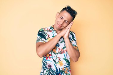 Genç, yakışıklı, Latin, yaz kıyafetleri içinde uyuyan, yorgun, hayal kuran ve elleriyle poz veren, kapalı gözlerle gülümseyen adam.. 