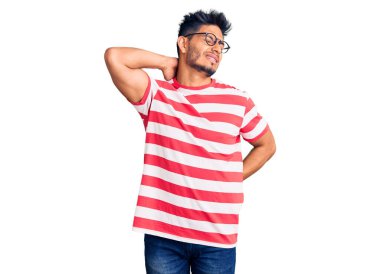 Yakışıklı Latin Amerikalı gündelik kıyafetler ve gözlük takan boynu ağrıyan, eliyle boynuna dokunan, kas ağrısı çeken genç bir adam. 