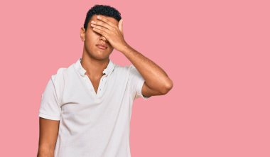 Genç Arap adam gündelik giysiler giyip gözlerini eliyle kapatıyor, ciddi ve üzgün görünüyor. Görme, saklama ve reddetme konsepti 