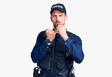 Polis üniforması giyen genç yakışıklı savunma hareketleriyle dövüşmeye hazır kızgın ve üzgün yüzlü, sorundan korkan. 