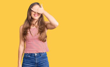 Gündelik kıyafetler giyen güzel beyaz bir kadın. Gülümsüyor ve elleri yüzünde, şaşırmak için gözleri kapatıyordu. kör kavram. 