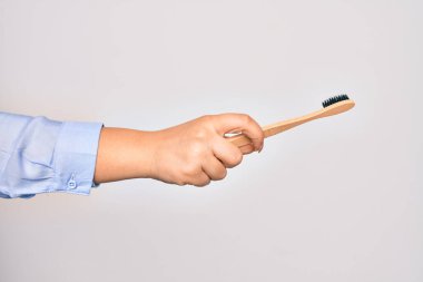 Beyaz arka plan üzerinde diş fırçası tutan beyaz bir kadının eli