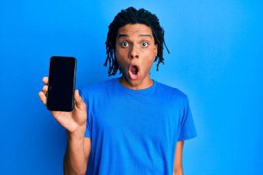Genç Afro-Amerikan adam elinde akıllı telefonuyla boş ekran gösteriyor. Şaşırmak için ağzı açık ve korkmuş. İnanmayan yüz. 