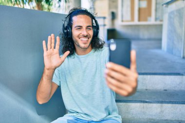 Genç İspanyol adam gülümsüyor. Şehirde akıllı telefon görüşmeleri yapıyor..