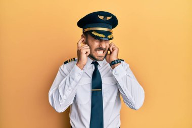Yakışıklı İspanyol pilot üniforması giyiyor. Yüksek sesli müzik sesi için kulakları parmaklarıyla kapatıyor. sağır kavramı. 